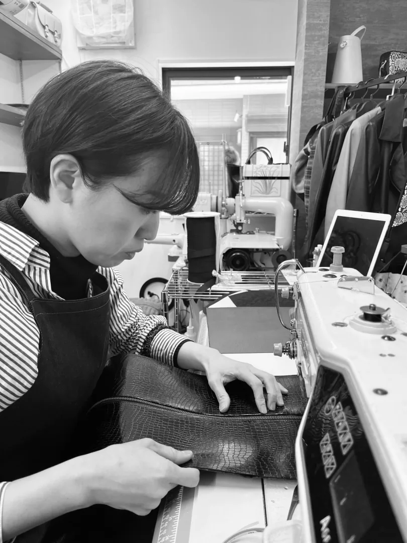 工房のミシンに向かい、クロコ型押しの革を縫い進める革職人の黒沢さだみ